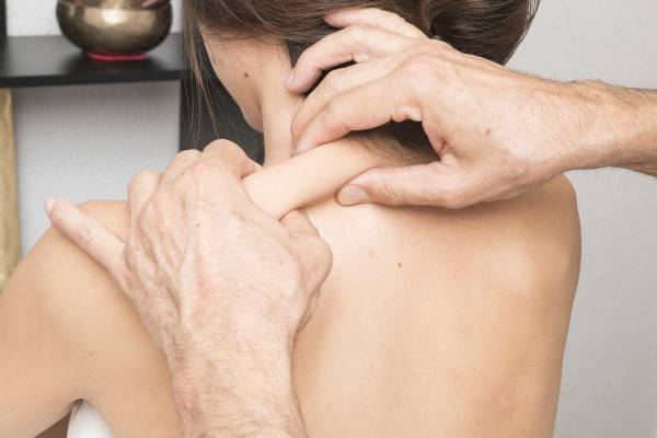 Kvinnlig patient som får medicinsk massageterapi på ena axeln hos en klinik i Halmstad